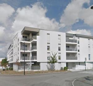 a white apartment building on the corner of a street at Le Petit Zénith in Saint-Herblain