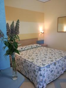 1 dormitorio con 1 cama con un jarrón de flores sobre una mesa en Masseria Asciano en Ostuni