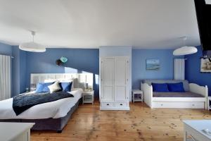 1 dormitorio con paredes azules, 1 cama y un banco en Chambres d'hôtes Villa de Vienne-en-Arthies en Vienne-en-Arthies