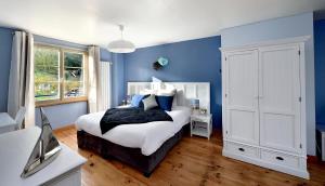 een blauwe slaapkamer met een bed en een televisie bij Chambres d'hôtes Villa de Vienne-en-Arthies in Vienne-en-Arthies