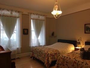 a bedroom with two beds and a chandelier at B&B Chez Hubert in Quebec City