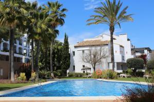 a swimming pool in front of a building with palm trees at La Concha Vista La Quinta in Marbella