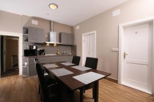a dining room table with chairs and a kitchen at Boutique Apartments Oradea in Oradea +12 photos