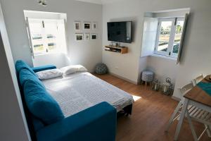 a bedroom with a blue couch and a television at Casa Ver o Mar in São Mateus