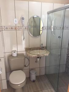 a bathroom with a toilet and a sink and a mirror at Mirante Hotel in Santa Vitória do Palmar +9 photos