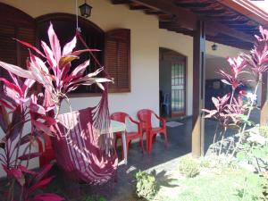a porch of a house with a table and red chairs at Pousada Tamboril in Brumadinho