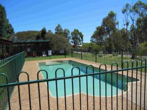 a swimming pool behind a fence in a park at Twin Trees Country Cottages in Pokolbin