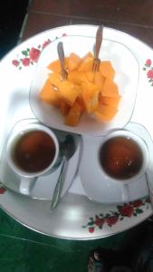 um prato com duas chávenas de café e um prato de fruta em Hotel Edelweis 2 Bajawa em Bajawa
