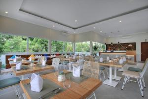 a restaurant with tables and chairs and windows at Tapa Tepi Kali Canggu in Canggu