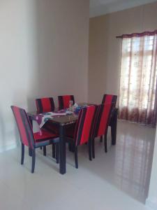 a dining room table and chairs with red cushions at D'Airport Homestay & Transit Rooms in Kota Bharu