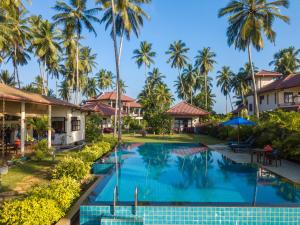 an image of a swimming pool at a resort with palm trees at Lanka Beach Boutique Bungalows & Grand Villa in Tangalle