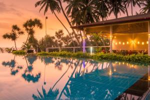 a swimming pool with a balcony overlooking the ocean at Lanka Beach Bungalows in Tangalle