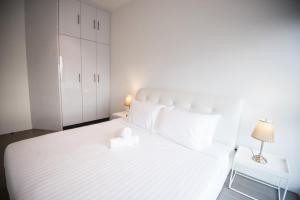 a white bedroom with a white bed and a lamp at KL Sentral Bangsar Suites (EST) by Luxury Suites Asia in Kuala Lumpur