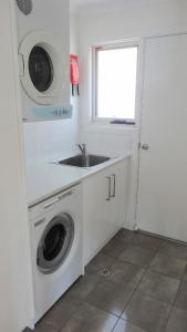 a kitchen with a sink and a washing machine at Millpond. in Penneshaw