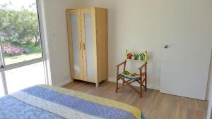 a bedroom with a bed and a chair and a window at Millpond. in Penneshaw