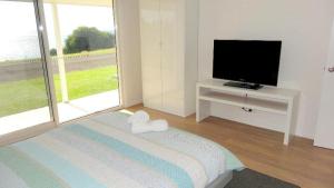 a white room with a tv and a bed and a flat screen television at Millpond. in Penneshaw