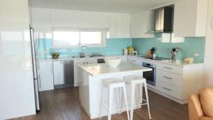 a kitchen with a counter and two stools in it at Millpond. in Penneshaw