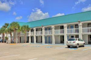 a building with a car parked in a parking lot at Regency Inn & Suites - Saint Augustine in Saint Augustine Beach