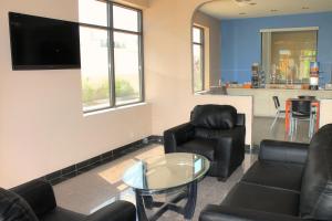 a living room with black leather chairs and a flat screen tv at Regency Inn & Suites - Saint Augustine in Saint Augustine Beach