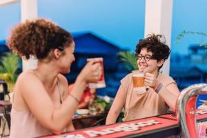 un homme et une femme assis à une table avec des boissons dans l'établissement THE PLACE Hostel & Rooftop Bar, à Battambang