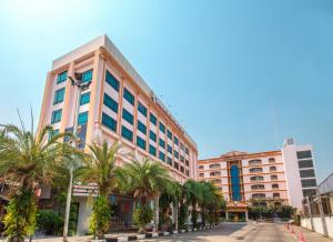 a large building with palm trees in front of it at Chiangmai Ratanakosin Hotel in Chiang Mai