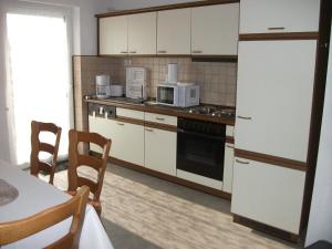 eine Küche mit weißen Geräten sowie einem Tisch und Stühlen in der Unterkunft Ferienwohnung Fischer mit Balkon in Hambach