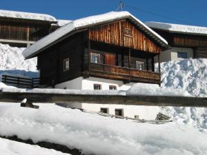 a wooden cabin with snow on the roof at Haus an den Wassermühlen in Maria Luggau