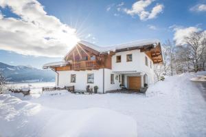 a house in the snow with the sun behind it at Appartement Jäger in Flachau