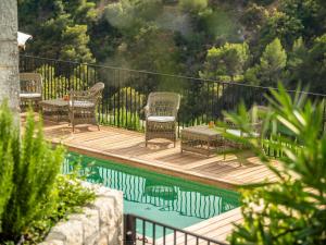 a deck with wicker chairs and tables next to a pool at Auberge De Tourrettes in Tourrettes-sur-Loup