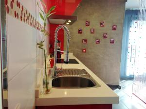 eine Küche mit einem Waschbecken und einer roten Wand in der Unterkunft Atico Deluxe San Basilio in Córdoba