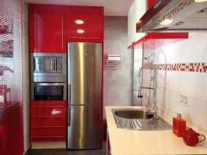 eine Küche mit roten Schränken und einem Kühlschrank aus Edelstahl in der Unterkunft Atico Deluxe San Basilio in Córdoba