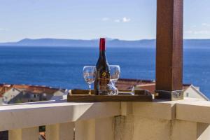 butelkę wina i 2 kieliszki na balkonie w obiekcie Apartmani Sani Bol w Bol