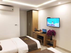 a hotel room with a bed and a television on the wall at Trang Ngan Hotel by THG in Danang