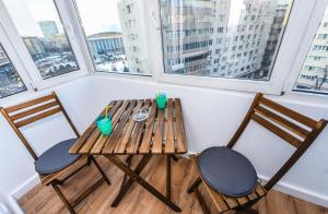 布加勒斯特豪华住宿公寓　的窗户间配有一张木桌和两把椅子