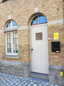 uma porta branca num edifício de tijolos com duas janelas em ieperlee 23 Holiday Home em Ypres