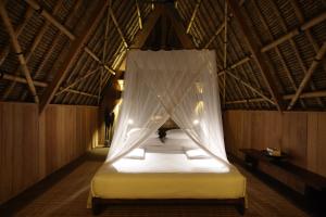 a bed in a room with a mosquito net at Jeeva Beloam Beach Camp in Tanjung Ringgit