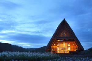 a thatched house with lights in a field of grass at Jeeva Beloam Beach Camp in Tanjung Ringgit