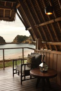 a porch with a couch and a table and the ocean at Jeeva Beloam Beach Camp in Tanjung Ringgit
