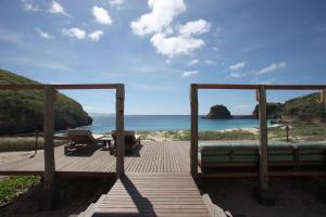 a wooden deck with a bed and a view of the ocean at Jeeva Beloam Beach Camp in Tanjung Ringgit