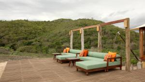 a deck with couches and tables on a hill at Jeeva Beloam Beach Camp in Tanjung Ringgit