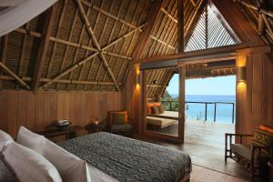 a bedroom with a bed and a view of the ocean at Jeeva Beloam Beach Camp in Tanjung Ringgit