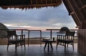 a table and chairs on a porch with a view of the ocean at Jeeva Beloam Beach Camp in Tanjung Ringgit