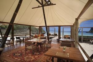a restaurant with tables and chairs and a view of the ocean at Jeeva Beloam Beach Camp in Tanjung Ringgit