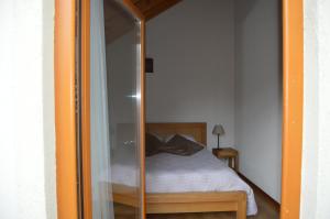 Una puerta de cristal que conduce a una cama en un dormitorio en Le Pressoir des 4 Saisons, en Berrwiller