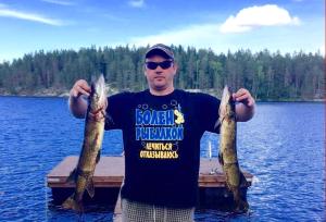 a man holding three large fish on a dock at Valteri in Enonkoski