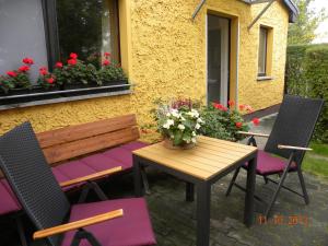 a wooden table and chairs with flowers on a patio at Ferienwohnungen Pilke in Oranienburg