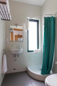 a bathroom with a green shower curtain and a sink at H18 in Horta