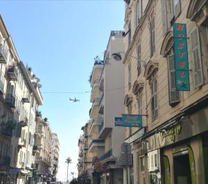 un avión está volando sobre una calle con edificios en Meyerbeer Beach, en Niza