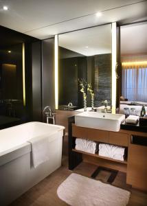 a bathroom with a large tub and a large mirror at Shenzhen Dameisha Kingkey Palace Hotel in Shenzhen