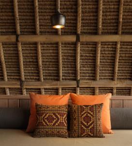 two pillows on a couch in front of a wall at Jeeva Beloam Beach Camp in Tanjung Ringgit